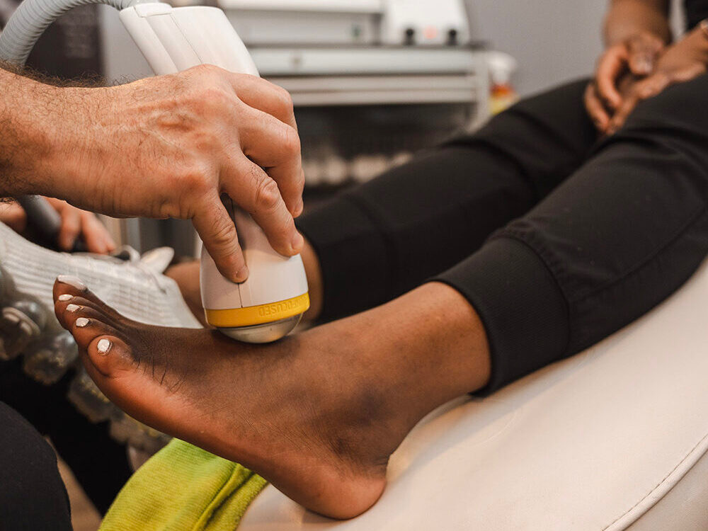 Dr. Joe Martin administering SoftWave shockwave therapy treatment to a patient at FootRejuv South Florida